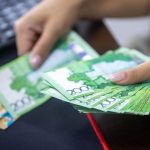 Person counting stacks of Uzbekistani som banknotes, showcasing financial transactions. — Why should you consider joining a f
