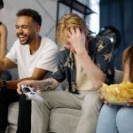 Diverse group of friends having fun playing video games indoors, sharing laughter and snacks. — Why should you spend your tim
