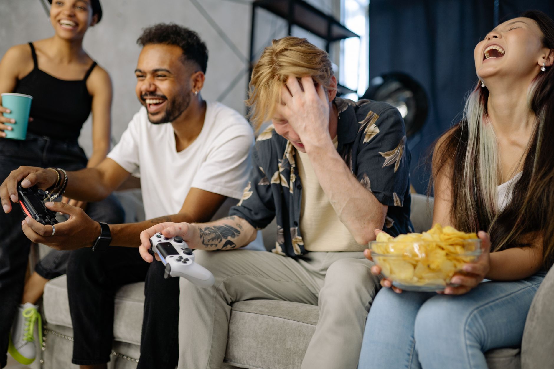 Diverse group of friends having fun playing video games indoors, sharing laughter and snacks. — Why should you spend your tim