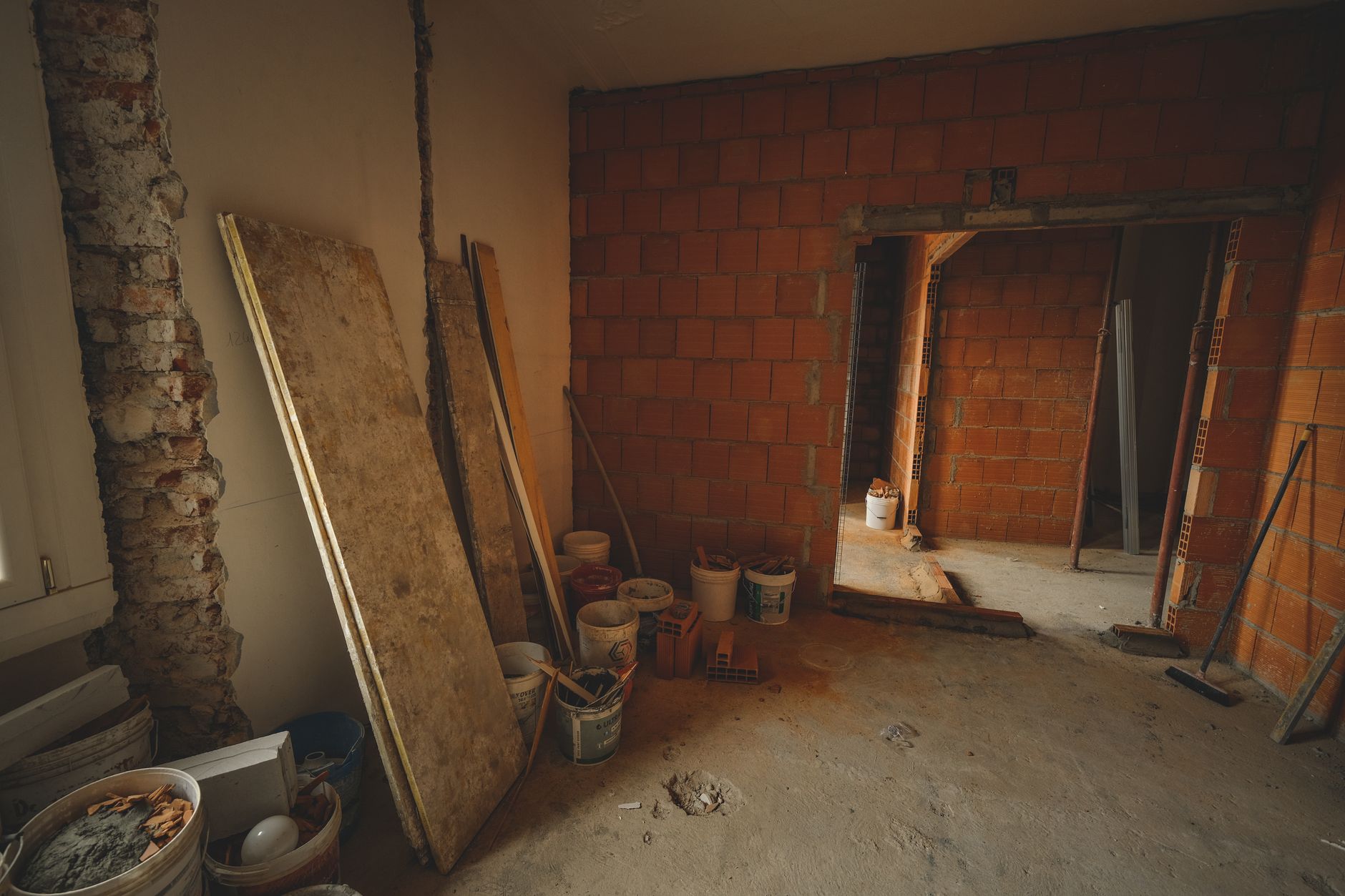 A red brick wall under construction with tools and materials scattered around in a renovation project. — WHY TIGER AND LEOPAR
