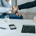 Business meeting with handshake and financial analysis displayed on a tablet. — Your Guide to the Best Nuru Massage Spots in