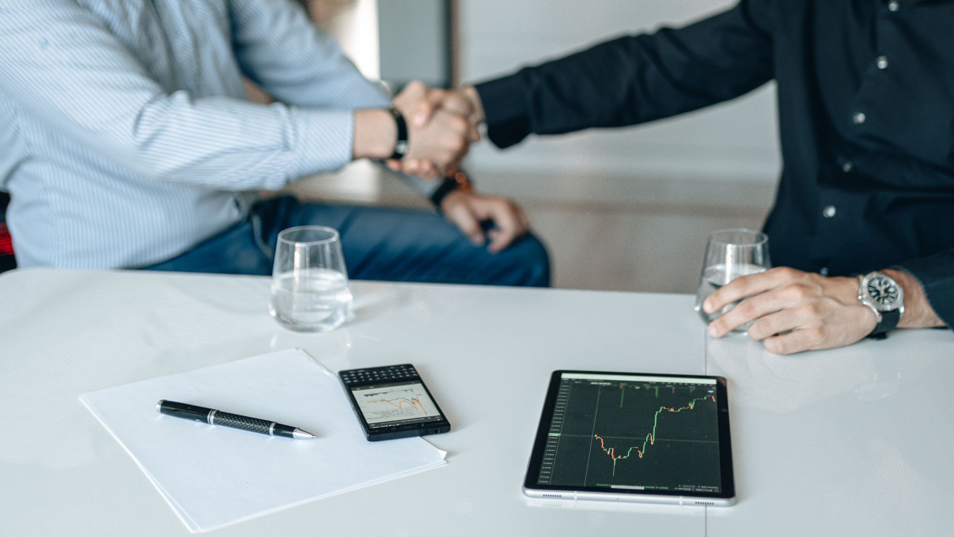 Business meeting with handshake and financial analysis displayed on a tablet. — Your Guide to the Best Nuru Massage Spots in